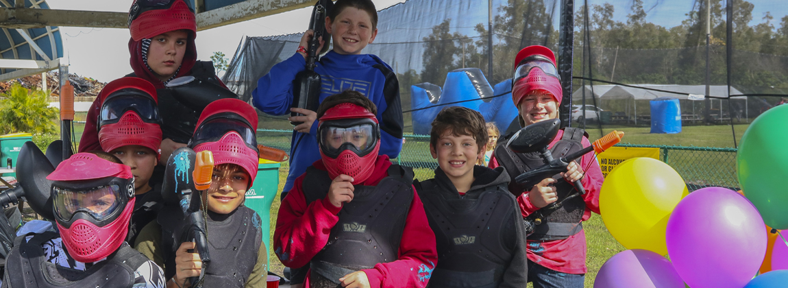 Kids birthday party celebrating with paintball gear and balloons at Fort Myers Paintball Park