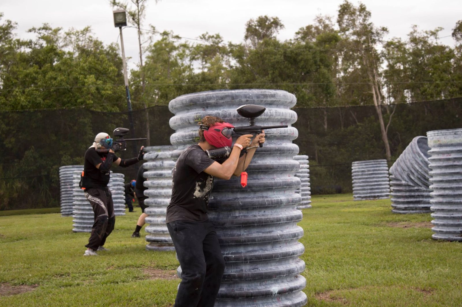 Paintball players taking aim behind inflatable bunkers at Fort Myers Paintball Park