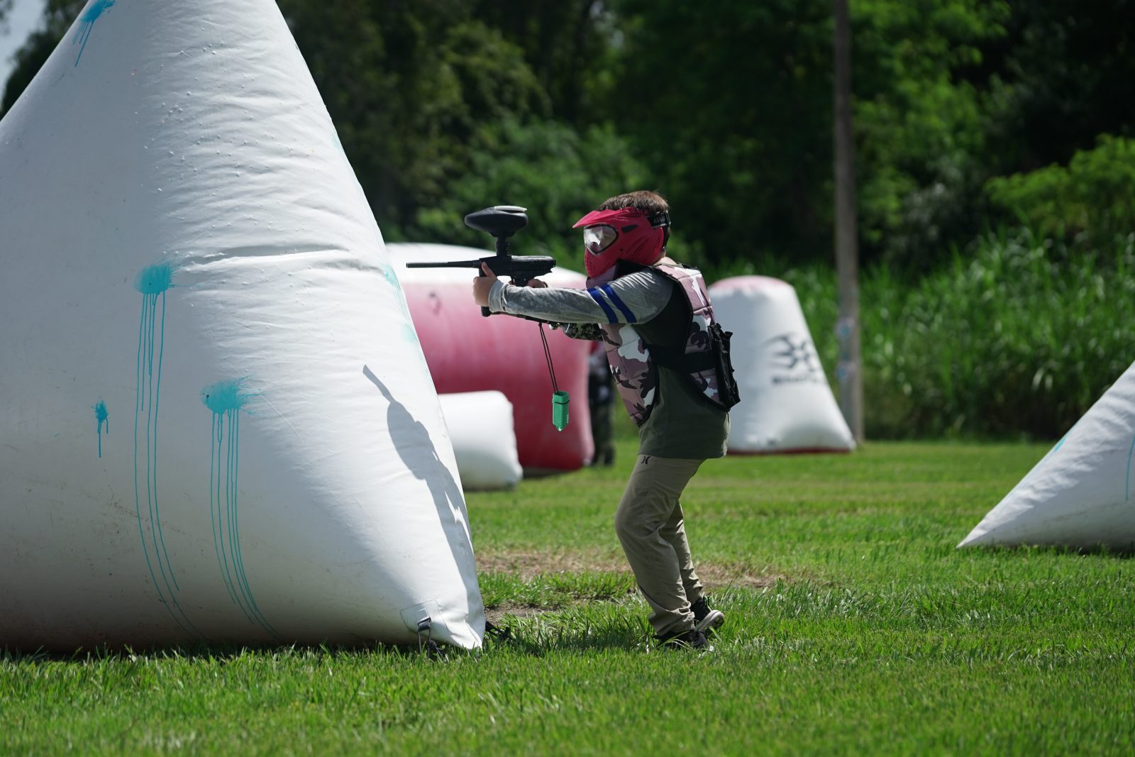 Paintball player taking aim from behind an inflatable bunker at Fort Myers Paintball Park