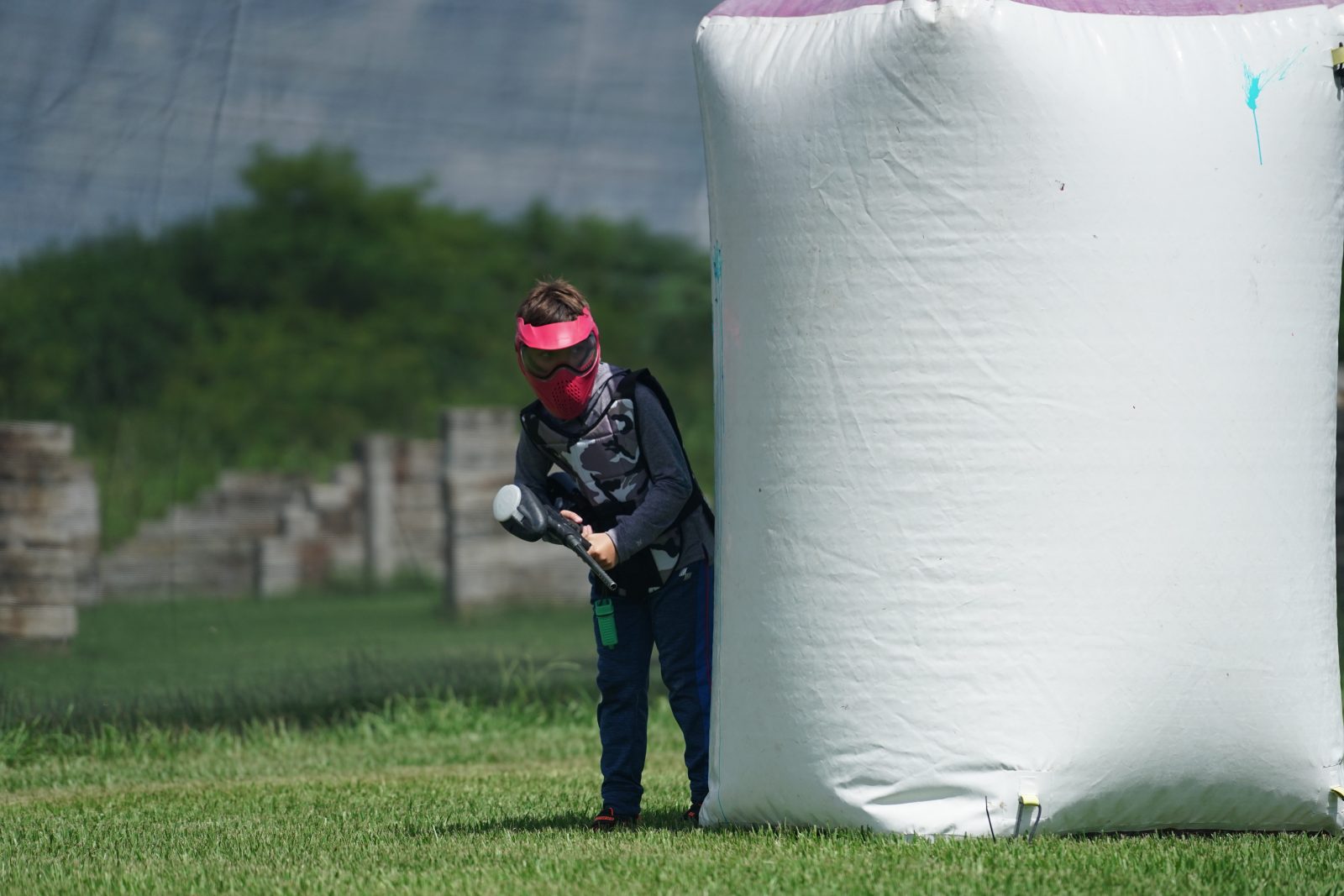 Young paintball player using an inflatable bunker for cover at Fort Myers Paintball Park